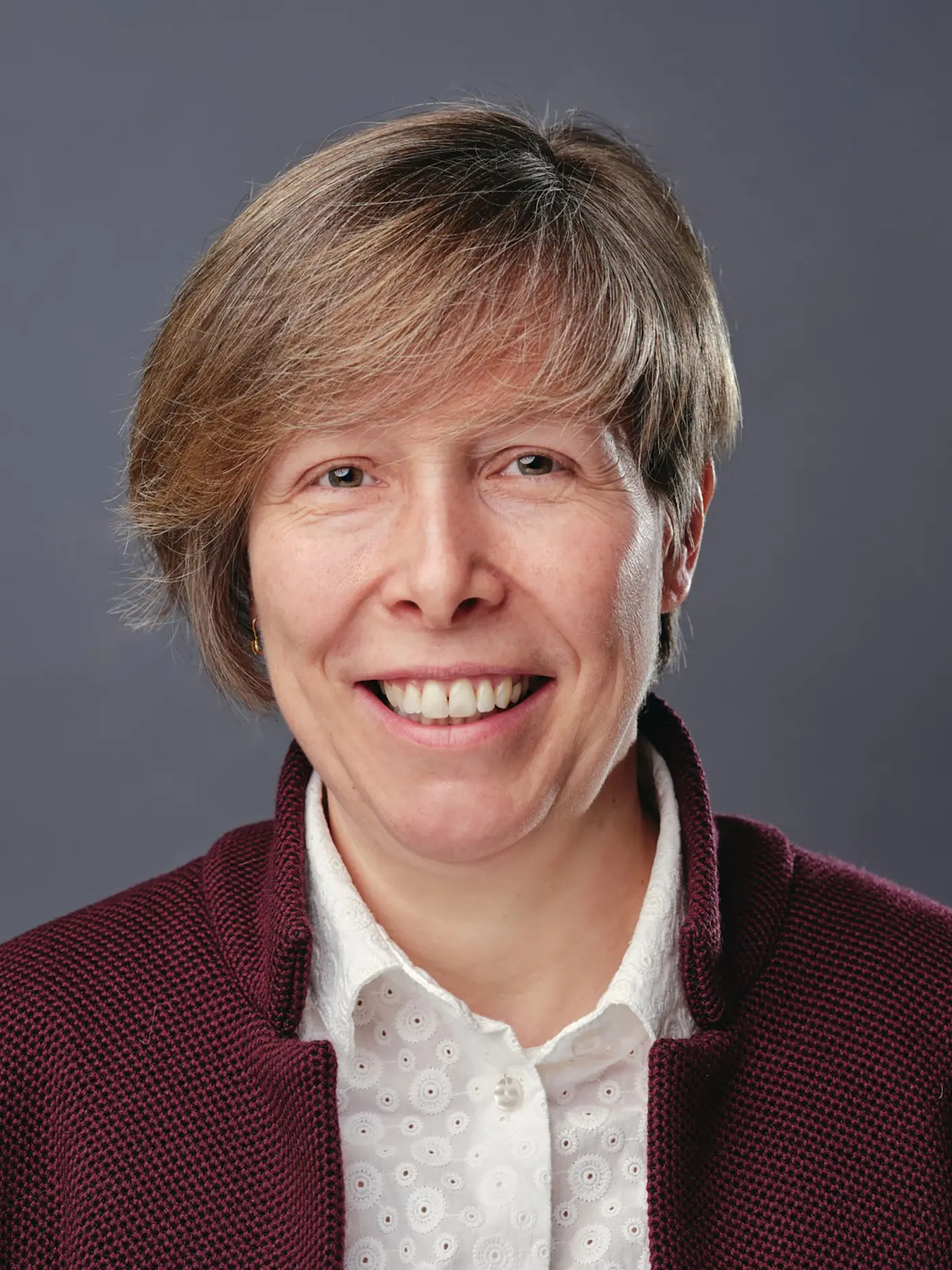 Non so chi sia. Rappresenta una persona con capelli corti e castani, che sorride, indossando una maglia rossa e una camicia bianca. Lo sfondo è grigio.