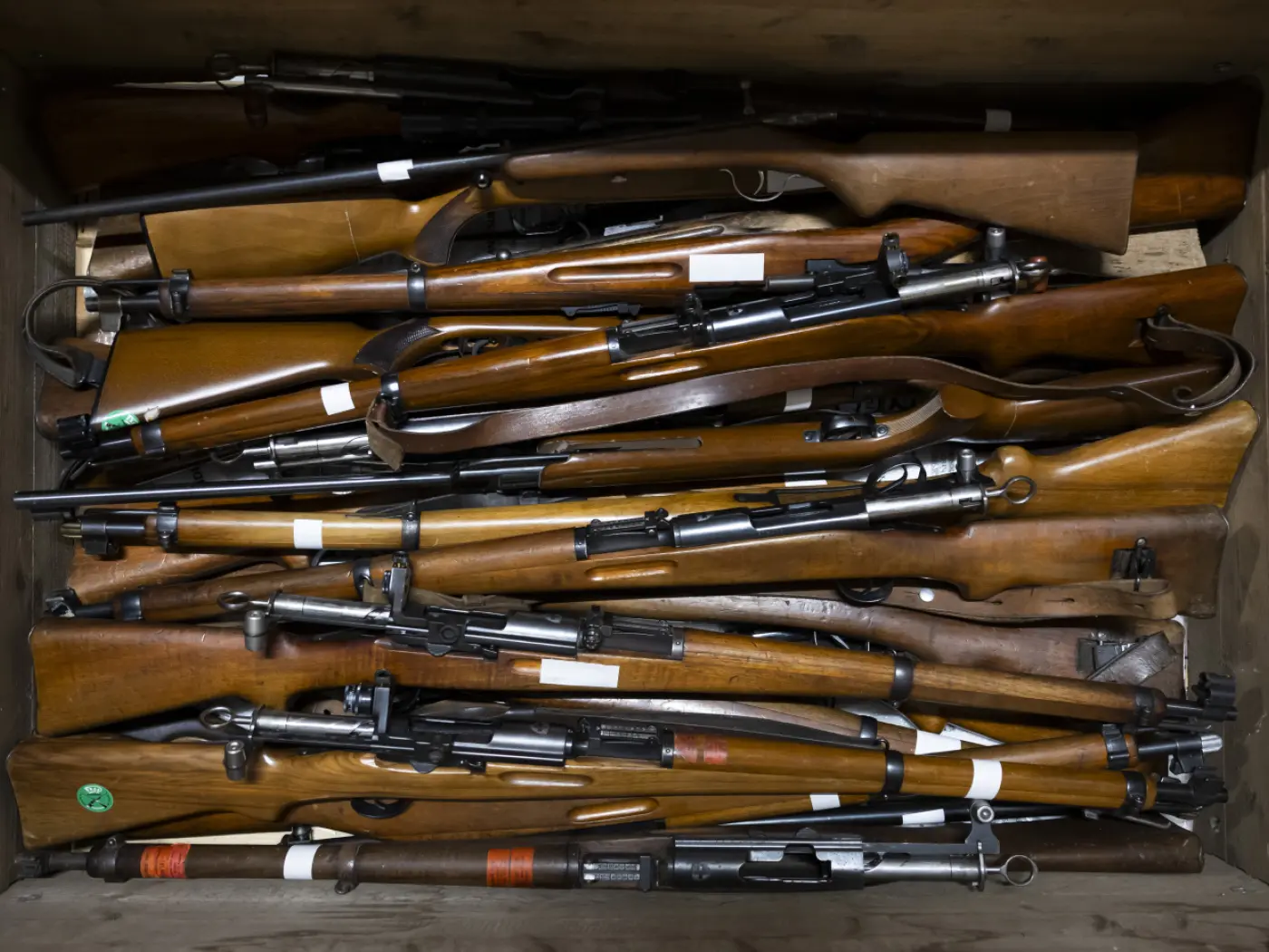 Fucili di diverse dimensioni e modelli disposti ordinatamente in una cassa di legno.