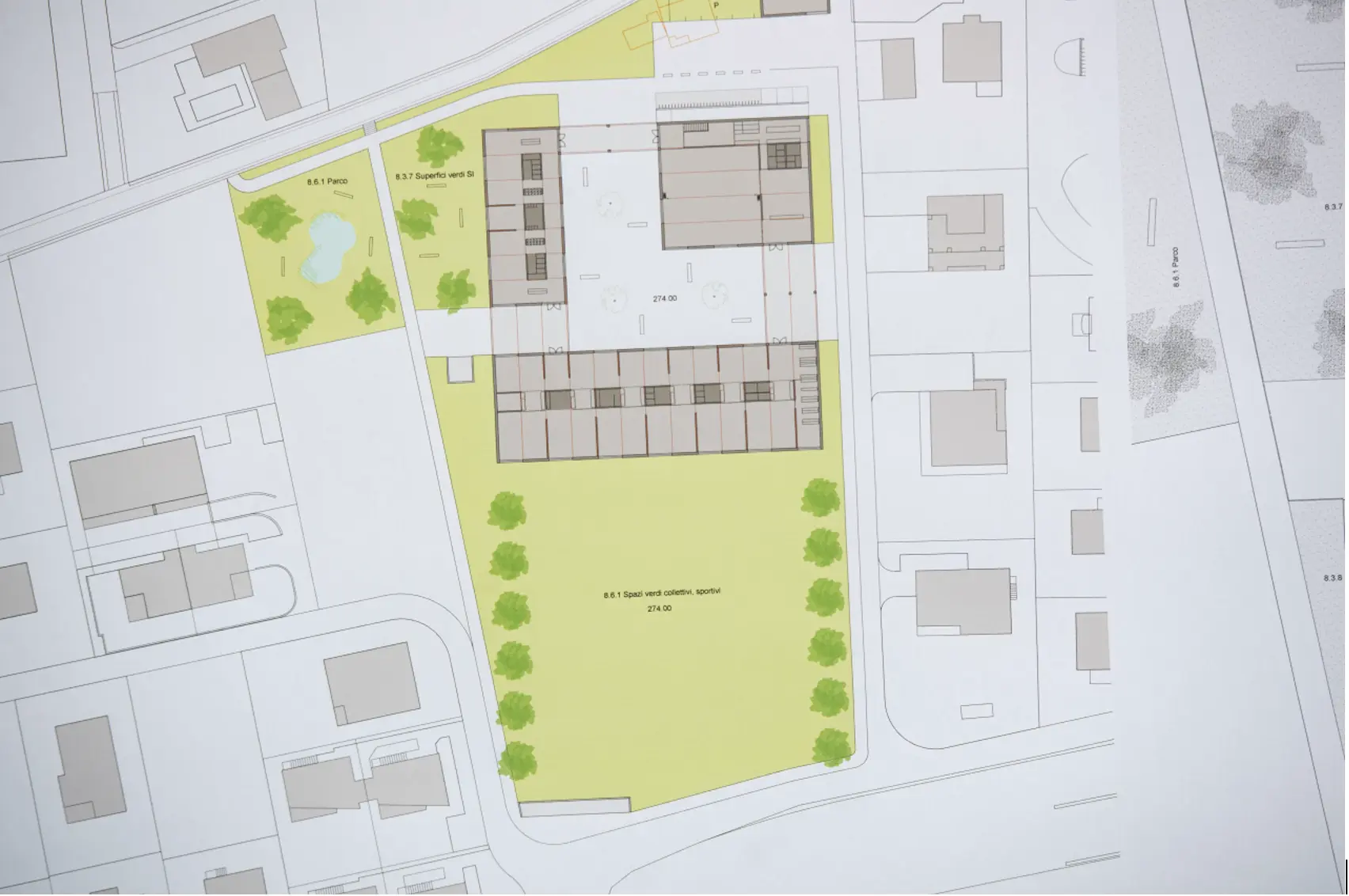 Mappa progettuale di un'area urbana, con edifici, aree verdi e strade evidenziate. Diversi lotti residenziali sono disposti attorno a uno spazio centrale.