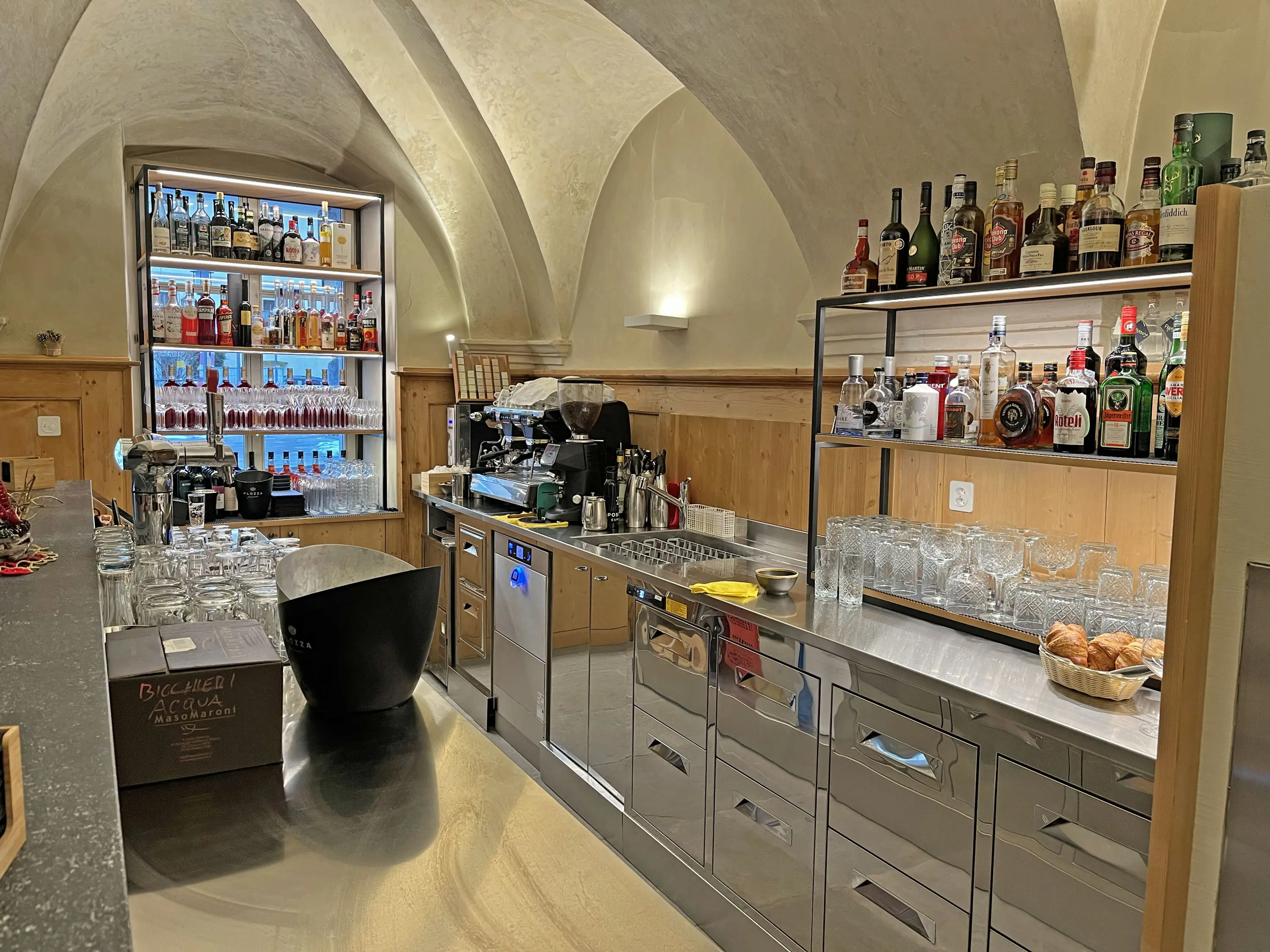 Bar moderno con attrezzature professionali. Mobili in acciaio inox, scaffali illuminati con bottiglie di alcolici e bevande. Macchina da caffè in primo