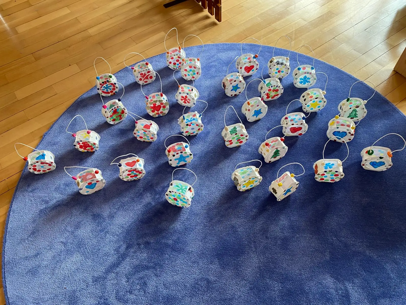 Un gruppo di piccoli cestini decorati con colori vivaci e motivi floreali, disposti ordinatamente su un tappeto blu.