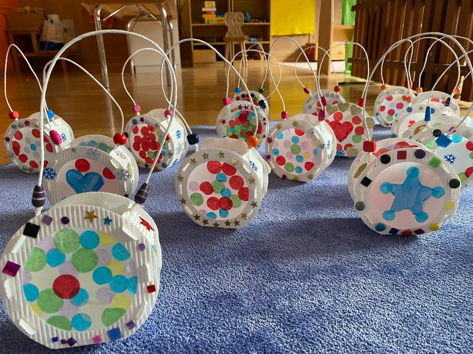 Lanterne decorate con colori vivaci e adesivi, disposte su un tappeto blu.