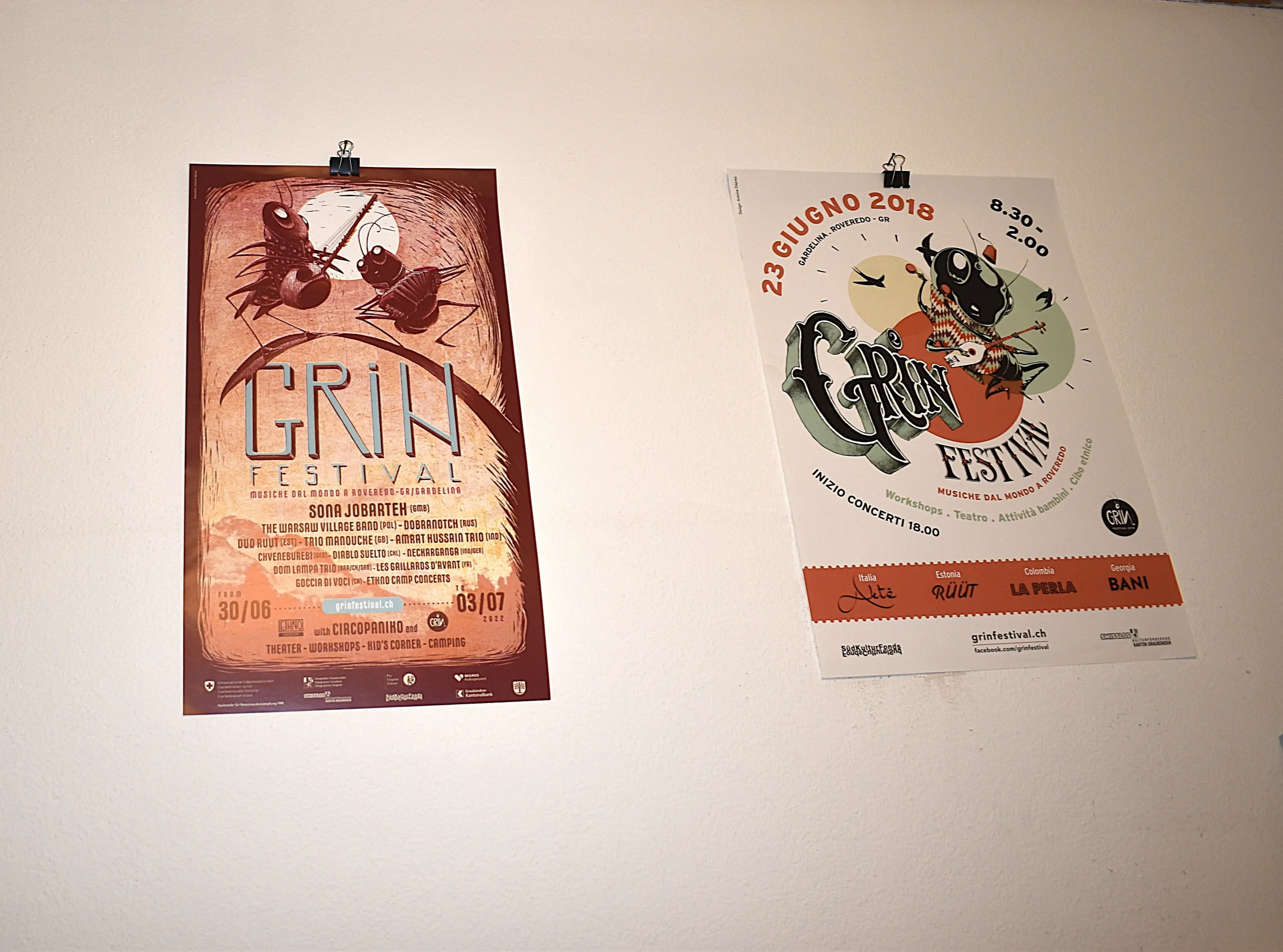 Manifesti del festival "Grin" appesi a una parete. Il primo manifesto, a sinistra, ha un design artistico con insetti, mentre il secondo, a destra, include informazioni dettagliate sulla data e l'orario dell'evento.