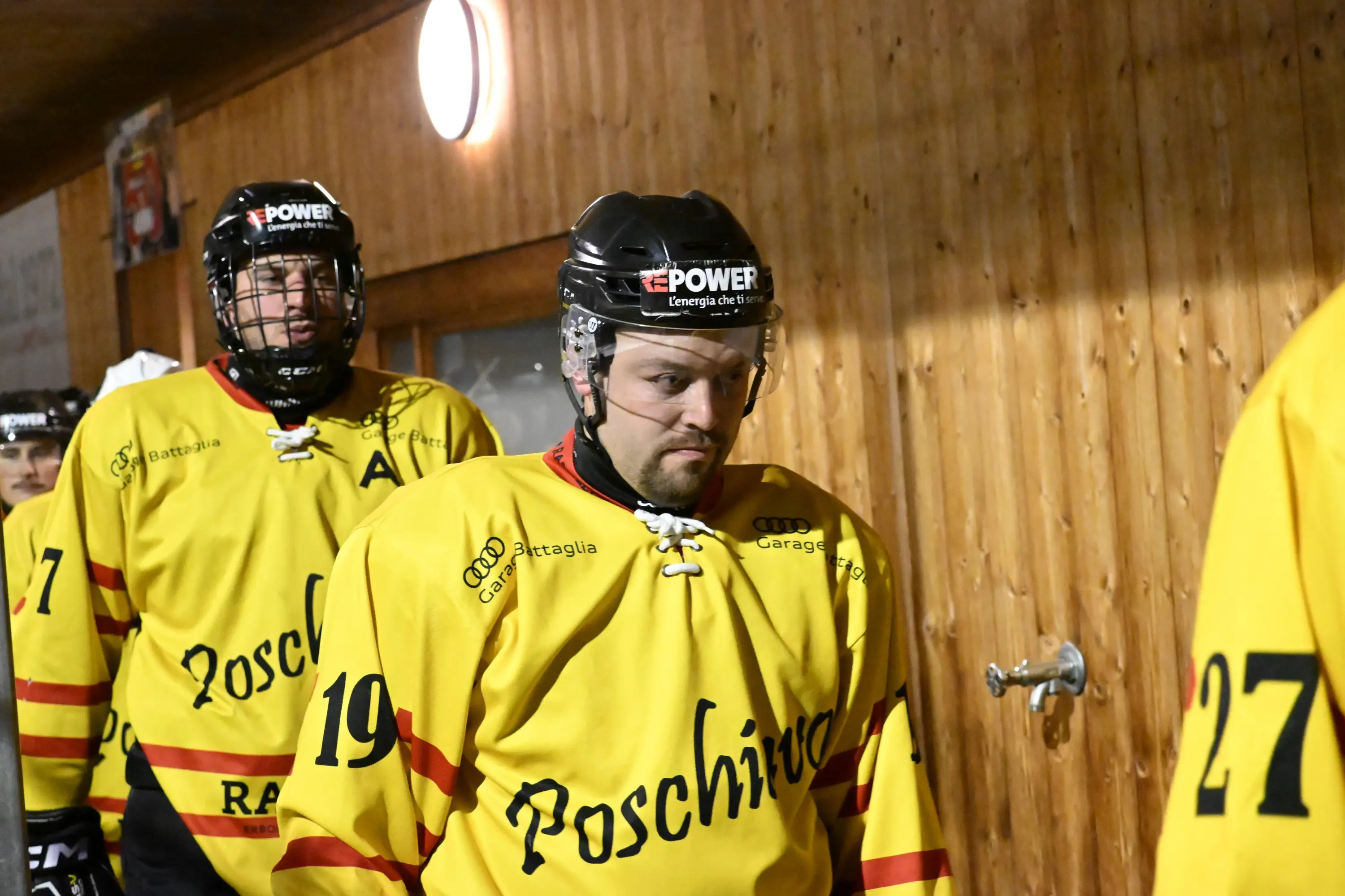 Giocatori di hockey su ghiaccio in divise gialle mentre entrano in campo, con espressioni concentrate.