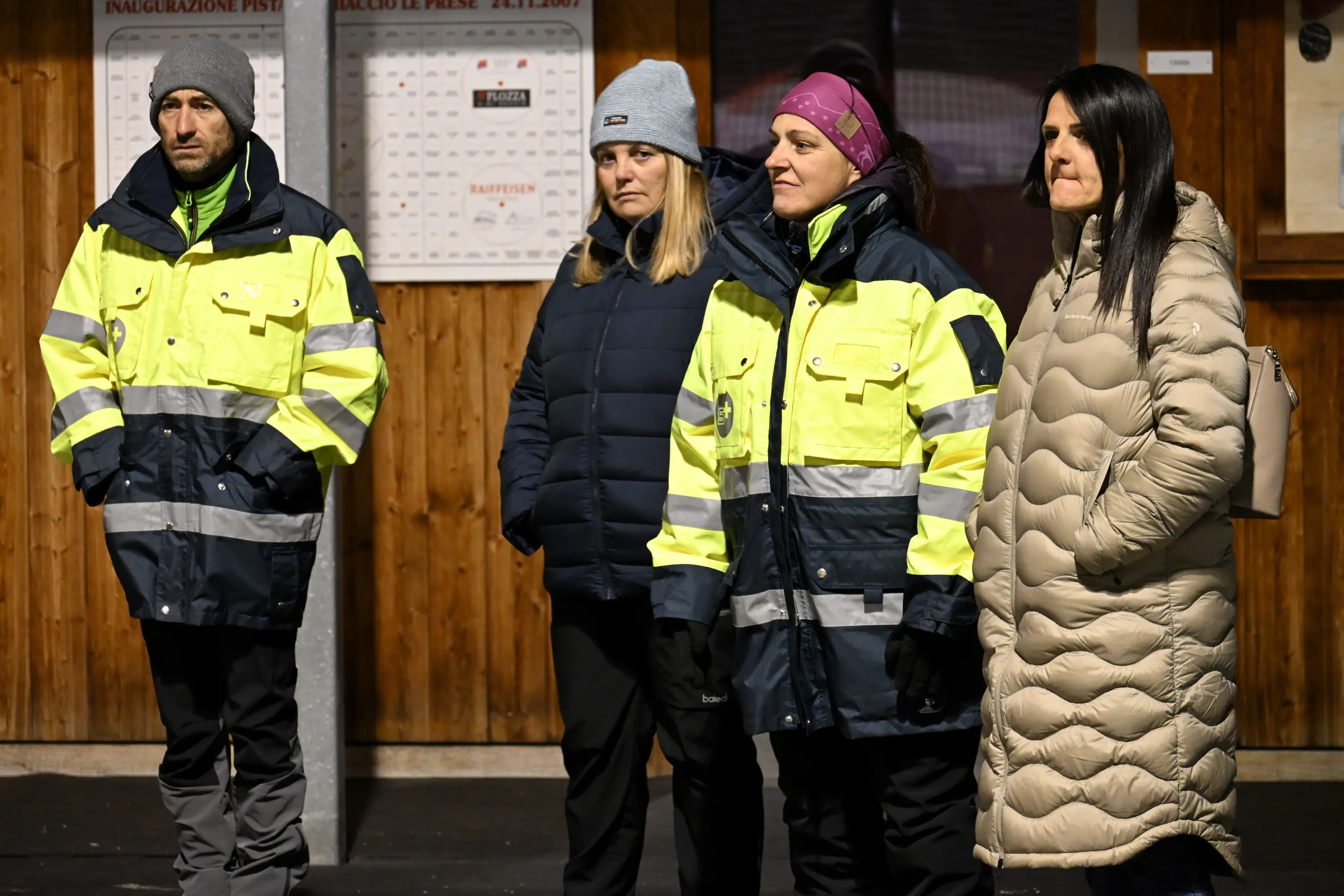 Quattro persone in abbigliamento outdoor ad alta visibilità, due indossano giacche gialle e nere, una indossa un cappello e l'altra una giacca imb